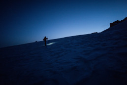 Bergsteiger in blauem Szenario mit Stirnleuchte im Schnee