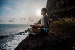 Ultraläufer Timothy Olson im Schneidersitz und in Yokapose meditierend an felsiger Küste