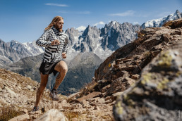 Ultraläufer Timothy Olson mit WIndbreaker-Jacke auf Felsen vor Bergpanorama