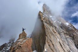 Bergsteiger Alexander Huber vor Felswand und Wolken