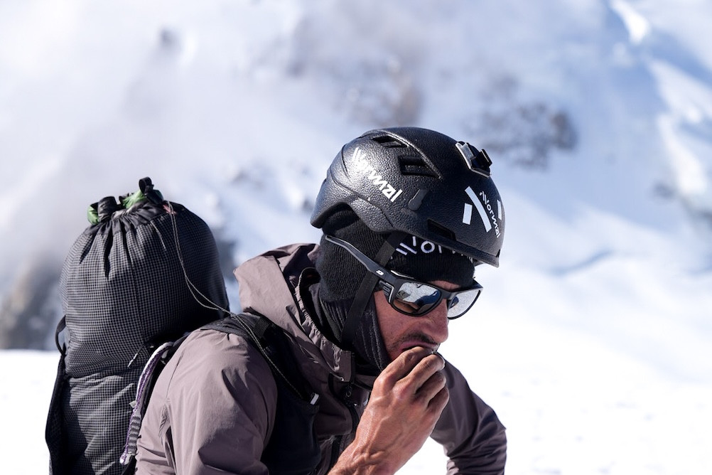 Ausdauerathlet und Keynote-Speaker Kilian Jornet kniet im Schnee vor Bergkulisse